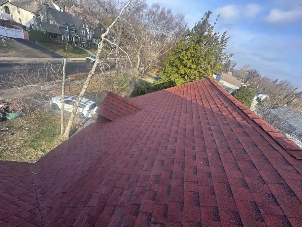 Aerial view along the ridge of a finished hip roof with red shingles and a dormer